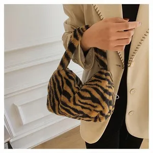 Detail view of stylish plush handbag with faux fur tiger print and wide handle strap