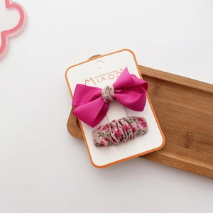 Detail of rose pink grosgrain bow and floral fabric hair clip set on display card