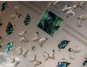 Macro shot of 5D butterfly nail stickers with gold outlines and 3D embossed diamond details
