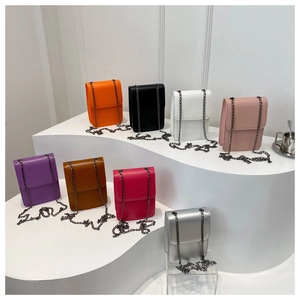 Multiple colorful mini chain crossbody bags displayed on a white tiered stand