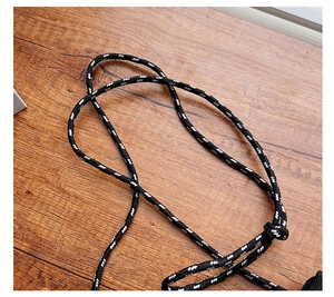 Close-up of black and white woven rope strap textured detail on wooden surface