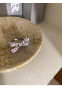 Detailed view of silver bow-knot ring with cubic zirconia on a marble tray