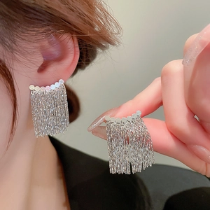Macro shot of silver geometric tassel earrings with cascading fine metal chain detail