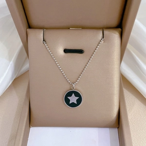 Détail d'un collier à billes argenté avec pendentif étoile en émail noir dans son écrin