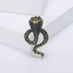 Macro shot of vintage gold snake brooch with green rhinestones on geometric blocks