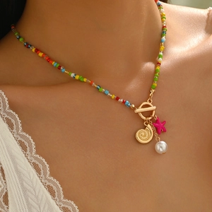Close-up of beaded necklace with gold conch, pink starfish and pearl on model