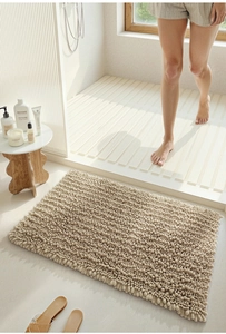 Absorbent beige chenille bath mat with soft textured surface on modern bathroom floor
