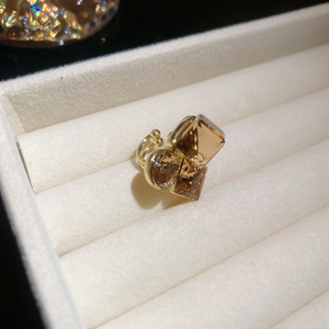 Macro detail of gold plated ear cuff with amber crystals on white velvet display