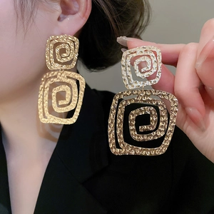 Detailed view of golden geometric square spiral earrings with a hammered metal texture