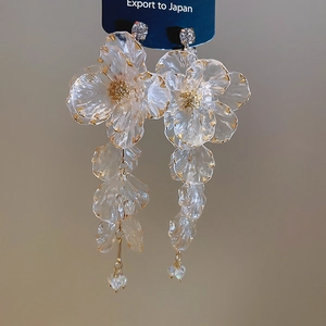 Close-up of crystal acrylic flower earrings with gold edges and long beaded tassels