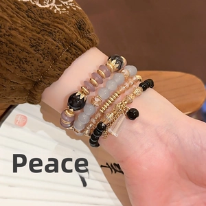 Close-up of four-piece beaded bracelet set with purple crystals and gold charms