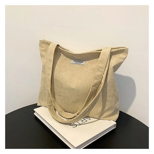 Detail of beige corduroy tote bag showing striped texture on minimalist background