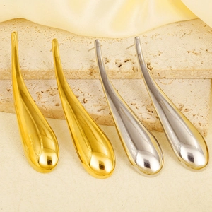 Macro view of polished gold and silver water drop earrings on textured stone