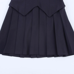 Detail of navy pleated mini skirt with academic style contrast panels and sharp pleats