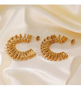 Detailed view of 18K gold plated C-shape spiral earrings on elegant beige silk fabric