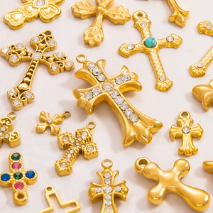 Dettaglio di vari ciondoli a croce placcati oro 18k con zirconi e pietre colorate incastonate