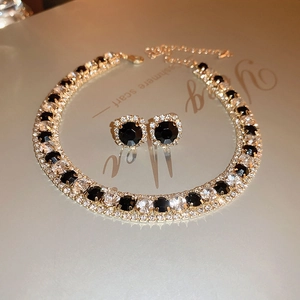 Close-up of vintage jewelry set with black and white crystals on gold base