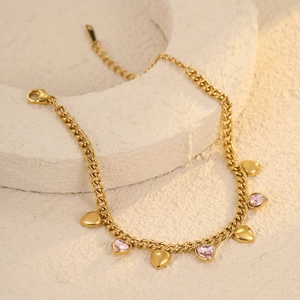 Close-up of golden chunky chain link bracelet with pink crystal heart charms