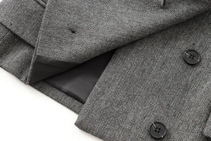 Detailed close-up of grey herringbone tweed fabric texture with premium black buttons