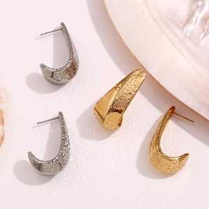 Macro view of C-shaped stainless steel earrings with textured surface and water droplets