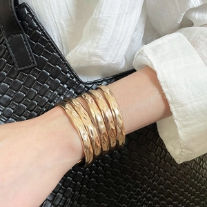Detailed close-up of five-piece gold bangle set with unique hammered texture and polished finish