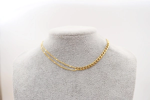 Detailed view of golden split-chain necklace with cuban links and sequins on a neck model
