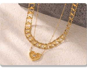 Detailed macro shot of vintage gold layered necklace with hollow heart pendant and gems