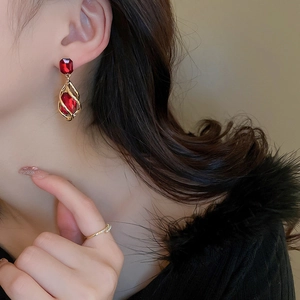 Macro shot of vintage style earrings with red crystals and gold metal on a model