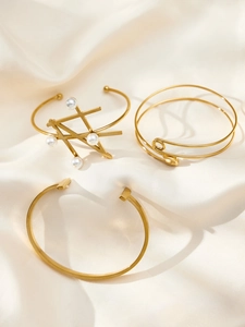 Detailed view of three minimalist 18k gold-plated bangles with pearls on silk fabric