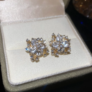 Macro shot of gold-plated flower stud earrings with white zircons in a velvet box