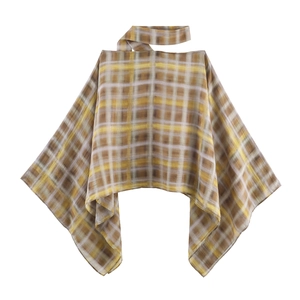 Detail des gelben Karo-Ponchos mit asymmetrischem Saum und leichter Stoffstruktur