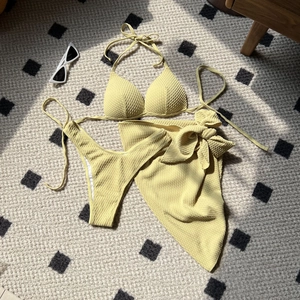 Detailed view of pale yellow waffle-textured three-piece bikini set and beach wrap skirt