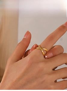 Detail of a golden crisscross ring featuring a unique hammered texture finish on model
