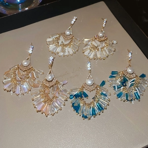 Close-up of shell-shaped long fringe earrings with crystals and pearls in three colors