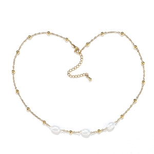 Macro shot of gold bead chain with three elegant white pearls and adjustable clasp