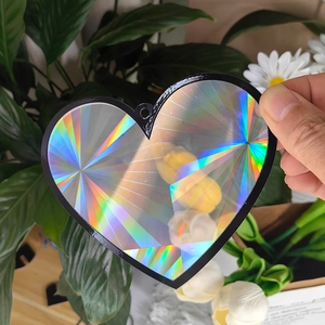 Close-up of heart-shaped crystal suncatcher with rainbow holographic finish and black frame