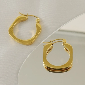 Macro shot of 18k gold plated stainless steel square hoop earrings on a mirrored surface