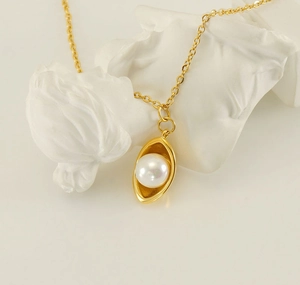 Détail du collier de perles plaqué or 18k présenté sur une sculpture d'art blanche