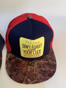 Close-up of tricolor snapback hat featuring embroidered patch and brown leather brim texture