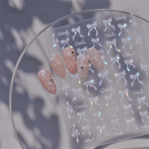 Macro view of shell light bow and butterfly nail decals applied on soft pink nails