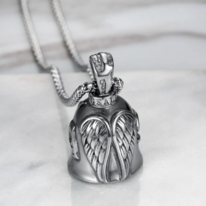 Macro shot of silver bell pendant with detailed eagle wing reliefs and chain detail