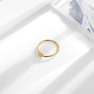 Minimalist 18k gold knot ring for women with polished finish on a white surface