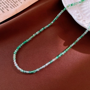 Detail of square green and white gradient beaded necklace on brown silk fabric