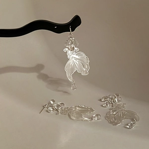 Detailed close-up of hollowed-out silver goldfish earring with transparent crystal pendant