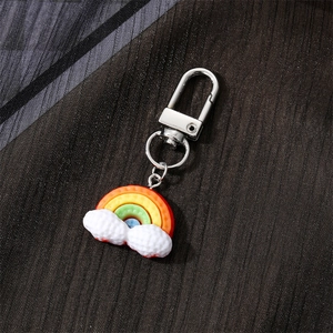 Cute rainbow cloud resin keychain with durable metal hardware on a textured dark background