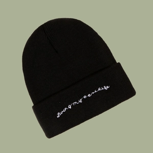 Detail view of black cuffed beanie with white 'Living my best life' cursive embroidery