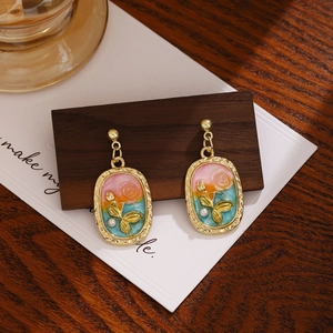 Detail view of retro rose enamel earring with pearl on dark walnut wood stand