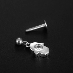 Macro shot of 316L stainless steel Hamsa Hand piercing stud with clear gemstone on black