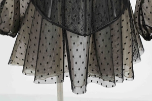 Detail of sheer black mesh fabric with polka dot pattern and delicate lace trim on dress