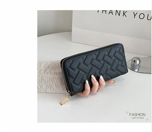 Detailed view of women's black long wallet featuring woven texture and gold zipper closure